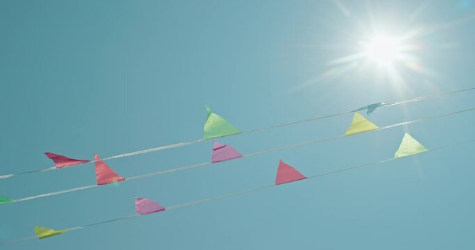 Colorful pennant flags strung across a bright, sunny sky.