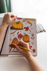 Hand drawing colorful autumn-themed illustrations in sketchbook