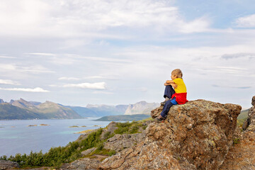 Family with children and pet, hiking Sukkertoppen trail on Senja island, Norway