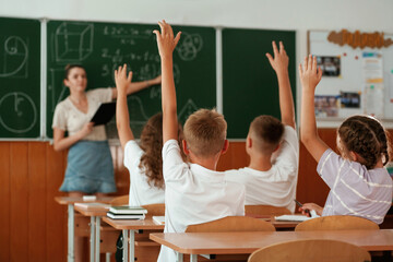 With hands up. Pupils, kids in the classroom together