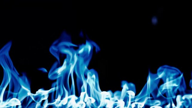 Gas burns with a bright blue flame. Blue fire is burning. Slow-motion video of bright blue flames against a black background. A wall of real fire with an abstract background. Super-slow motion video