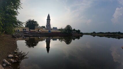 Obraz premium Serene sunset at the Hindu temple reflecting in the calm waters at dusk