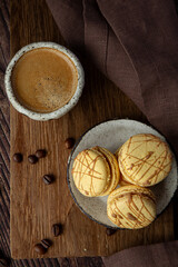 Light brown, beige french macaroons  on the dark background with cup of coffee