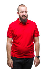 Obraz premium Young caucasian hipster man wearing red shirt over isolated background winking looking at the camera with sexy expression, cheerful and happy face.