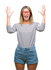 Young beautiful woman wearing glasses over isolated background celebrating mad and crazy for success with arms raised and closed eyes screaming excited. Winner concept