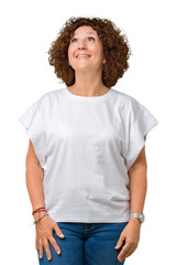 Beautiful middle ager senior woman wearing white t-shirt over isolated background smiling looking side and staring away thinking.