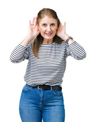 Middle age mature beautiful woman wearing stripes winter sweater over isolated background Trying to hear both hands on ear gesture, curious for gossip. Hearing problem, deaf