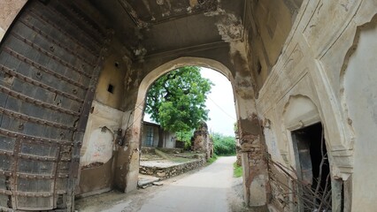 Exploring historic architecture at an ancient fort entrance in a lush green setting during the afternoon, Jaipur 

