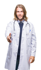 Young handsome doctor man with long hair over isolated background smiling friendly offering handshake as greeting and welcoming. Successful business.