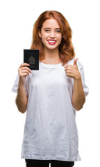 Fototapeta premium Young beautiful woman holding passport of canada over isolated background happy with big smile doing ok sign, thumb up with fingers, excellent sign