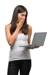 Young hispanic woman using computer laptop cover mouth with hand shocked with shame for mistake, expression of fear, scared in silence, secret concept