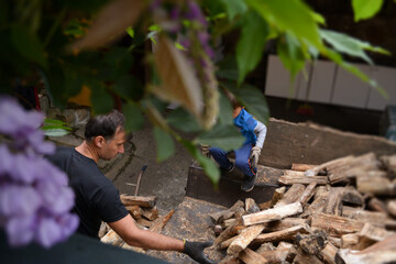 Todler boy with his father in work gloves stacking firewood against the background of a rural yard. The concept of family assistance, family values