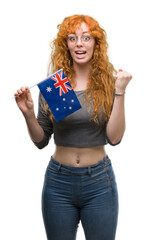 Young redhead woman holding flag of Australia screaming proud and celebrating victory and success very excited, cheering emotion