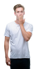 Fototapeta premium Young handsome blond man cover mouth with hand shocked with shame for mistake, expression of fear, scared in silence, secret concept