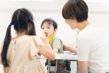 Obraz premium 0歳の弟に離乳食を与える姉