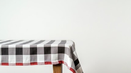  A checkered tablecloth is draped over a wooden table, shown against a white background 