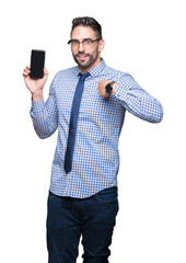 Naklejka premium Young business man showing smartphone screen over isolated background with surprise face pointing finger to himself