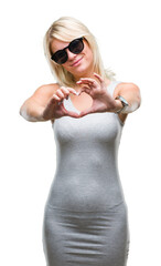 Young beautiful blonde woman wearing sunglasses over isolated background smiling in love showing heart symbol and shape with hands. Romantic concept.