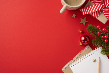 Top view of a holiday-themed desk featuring a notebook, coffee cup, and festive decorations creating a cozy Christmas atmosphere