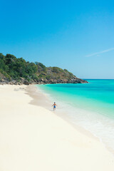 Young men in a swim short relaxing at beach with turquoise colored ocean and white sand. summer background and summer holiday concept.