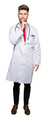 Fototapeta premium Young handsome doctor man wearing medical coat asking to be quiet with finger on lips. Silence and secret concept.