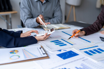 Business team analyzing financial data using calculator and documents in office meeting