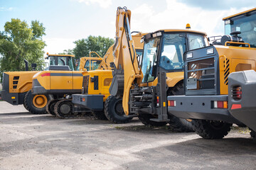 Yellow construction equipment stands in a row.