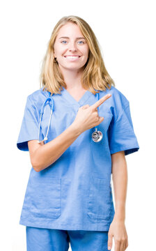 Beautiful young doctor woman wearing medical uniform over isolated background cheerful with a smile of face pointing with hand and finger up to the side with happy and natural expression on face
