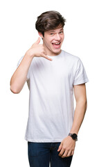 Fototapeta premium Young handsome man wearing casual white t-shirt over isolated background smiling doing phone gesture with hand and fingers like talking on the telephone. Communicating concepts.