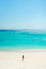 Man walks on a tropical beach with turquoise water and white sandy beach. summer background and summer holiday concept.