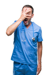 Middle age hoary senior doctor man wearing medical uniform over isolated background peeking in...