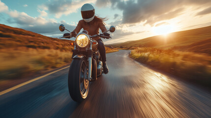 A female motorcyclist is riding on a curving road during sunset, capturing the thrill and freedom of the open road.