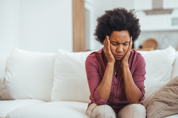 Worried Woman Sitting On Couch At Home Feeling Stressed