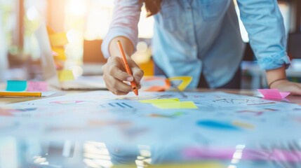 A person in a denim shirt brainstorms ideas, diligently writing on colorful sticky notes on a table filled with creative inspiration, illuminated by sunlight.