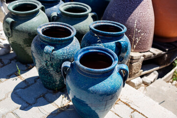 Ceramic pots for wine and beer on the street in the village. Handcrafted glazed vases in sunlight