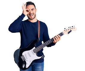Young handsome man playing electric guitar smiling happy doing ok sign with hand on eye looking through fingers