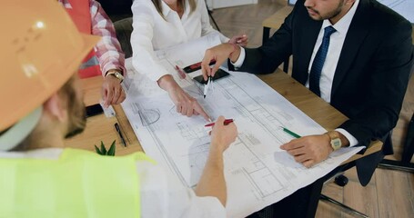 Woman engineers sitting around workplace and brainstorming over blueprint where attractive confident experienced man. Design office workflow concept.