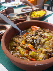 Stewed lamb with eggplant and green pepper in a ceramic bowl on the table during lunch. Homemade dishes. The concept of traditional Turkish cuisine. Vertical orientation.