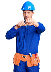 Young handsome man wearing worker uniform and hardhat suffering of backache, touching back with hand, muscular pain