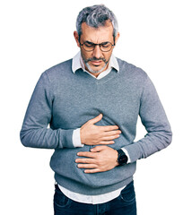 Middle age hispanic with grey hair wearing glasses with hand on stomach because indigestion,...