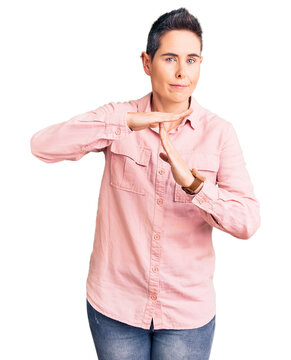 Young woman with short hair wearing casual clothes doing time out gesture with hands, frustrated and serious face