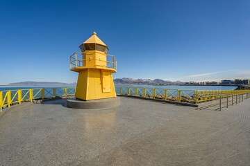 The historic yellow Hofoi lighthouse on the rocky shore of Reykjavik