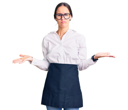 Beautiful brunette young woman wearing professional waitress apron clueless and confused with open arms, no idea concept.