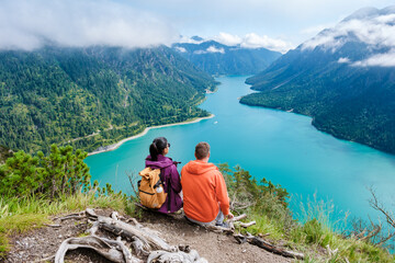 Fototapeta premium Couple enjoying a breathtaking view of Lake Plansee surrounded by mountains in Austria during summer