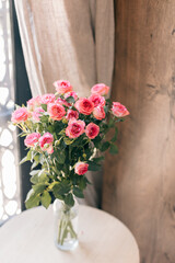 Tender pink Rose flowers in a vase near the window.