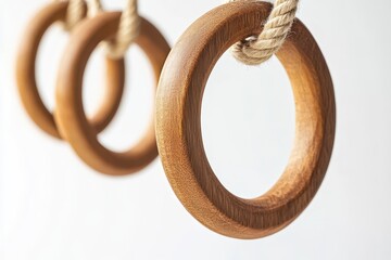 Wooden gymnastic rings hanging from a rope against white background for sports exercises