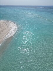 This image captures a breathtaking aerial view of a small, circular sandbank in the Maldives. 
