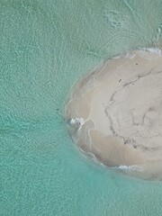 This image captures a breathtaking aerial view of a small, circular sandbank in the Maldives. 