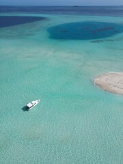 This image captures a breathtaking aerial view of a small, circular sandbank in the Maldives. 