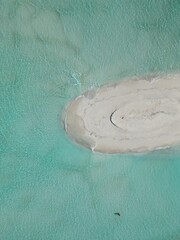 This image captures a breathtaking aerial view of a small, circular sandbank in the Maldives. 